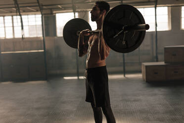 Starke Fitness Mann Training mit schweren Gewichten in Fitness-Club. Männlicher Athlet hält schweres Gewicht Langhantel im Fitnessstudio. - JLPSF00339