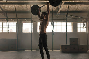 Ein fitter junger Mann trainiert mit schweren Gewichten im Cross-Training-Fitnessstudio. Ein muskulöser Mann trainiert mit einer Langhantel. - JLPSF00344