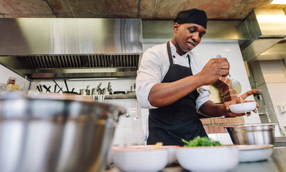 Afrikanischer männlicher Koch kocht Essen in einer Restaurantküche. - JLPSF00371