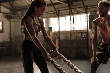 Fitness-Frau trainiert mit Kampfseilen im Fitnessstudio. Weibliches Training mit Personal Trainer im Fitnessclub. - JLPSF00377