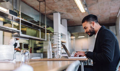 Business man sitting at restaurant working on laptop. Caucasian businessman at restaurant using laptop computer. - JLPSF00383