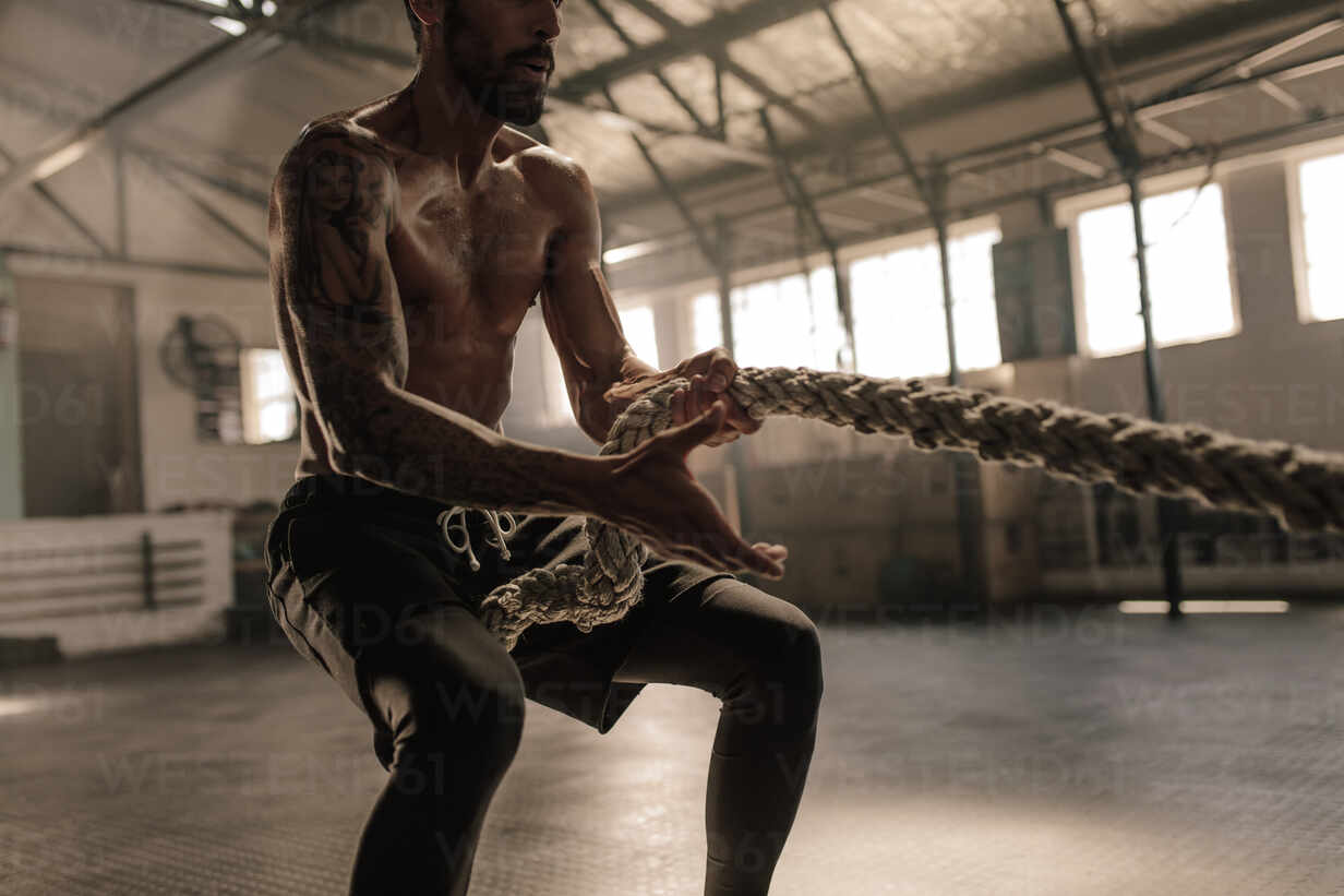 Athletic man with great physique pulling rope. Strong man pulling