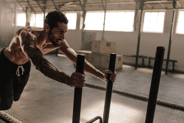 Ein Mann schiebt einen Schlitten in einem Fitnessstudio. Ein muskulöser Mann trainiert in einem Fitnessstudio. - JLPSF00399