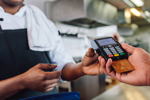 Hände eines Kunden, der die Restaurantrechnung mit einer Kreditkarte bezahlt. Ein Kunde, der mit einer Kreditkarte am Tresen eines Restaurants bezahlt. - JLPSF00401