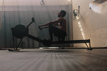 Muskulöser Mann benutzt Rudergerät im Fitnessstudio, fitter Mann beim Training im Fitnessclub. - JLPSF00410