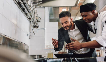 Manager riecht das Aroma des Gerichts Kochen auf dem Herd mit Koch. Koch bereitet Essen mit Besitzer riecht das Aroma im Restaurant Küche. - JLPSF00414