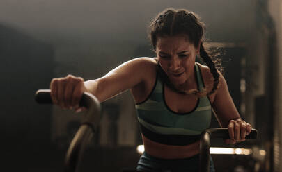 Fitness woman on gym bicycle doing exercise. Female putting full effort while exercising on gym air bike. - JLPSF00432