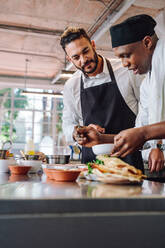 Zwei professionelle Köche arbeiten in einer Restaurantküche und kochen neue Gerichte in einer Großküche. - JLPSF00449