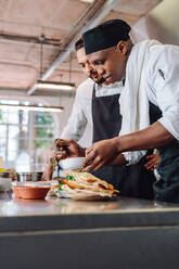 Zwei professionelle Köche arbeiten in einer Restaurantküche zusammen. Köche bereiten gemeinsam Essen zu. - JLPSF00450