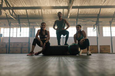 Drei junge Freunde, die sich nach dem Fitnesstraining ausruhen. Glückliche junge Leute, die nach dem Training im Fitnessstudio eine Pause machen. - JLPSF00452