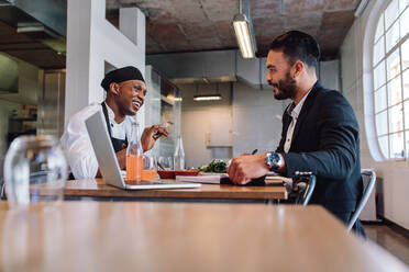 Restaurant business manager sitting and talking with chef. Restaurant owner having a conversation with employee. - JLPSF00459