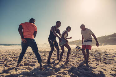 Junge Freunde spielen Fußball am Sandstrand. Afrikanische Menschen genießen ein Fußballspiel an einem Sommertag. - JLPSF00491