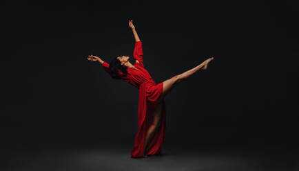 Contemporary female dancer performing over black background. Young woman dancing in studio. - JLPSF00496