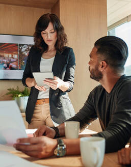 Beautiful businesswoman using digital tablet with man sitting at table in meeting room. Business people working in meeting room in office. - JLPSF00504