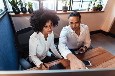 Aufnahme von zwei jungen Unternehmern, die zusammen am Schreibtisch sitzen und arbeiten. Mann und Frau arbeiten zusammen im Büro. - JLPSF00507