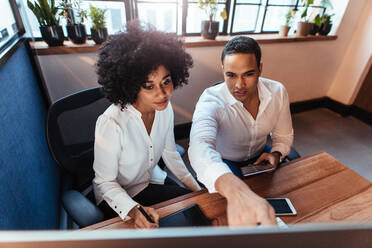 Shot of two young entrepreneurs sitting together and working at office desk. Man and woman working together in office. - JLPSF00507