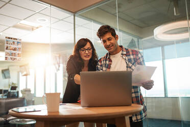 Young businessman and businesswoman working together on laptop in office. Couple of creative professionals working on new project. - JLPSF00598