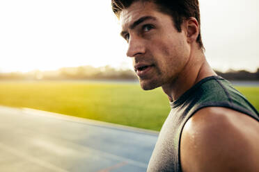 Closeup of a sprinter standing on a running track. Athlete looking away standing on the track. - JLPSF00667