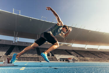 Runner using starting block to start his run on running track in a stadium. Athlete starting his sprint on an all-weather running track. - JLPSF00713