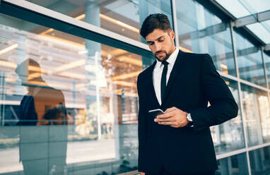 Geschäftsreisender, der auf sein Handy schaut. Kaukasischer Geschäftsmann, der auf dem Flughafen ein Mobiltelefon benutzt. - JLPSF00743