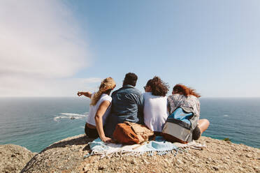 Group of friends on top of hill and enjoying view. Young people sitting on top of a mountain and looking at sea. - JLPSF00749