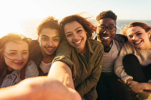 Cheerful friends taking selfie on a holiday. Group of men and women sitting outdoors on a summer day making self portrait. - JLPSF00750