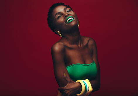 Schöne afrikanische Frau mit lebendigen Make-up. Schönheit Porträt der sinnlichen Modell mit bunten Make-up auf rotem Hintergrund. - JLPSF00773