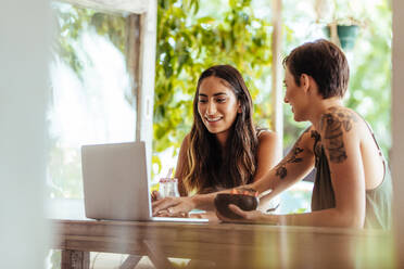 Two women sitting at a restaurant working on a laptop computer. Women sitting at a restaurant enjoying desserts. - JLPSF00826