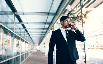 Geschäftsmann, der am Flughafen mit einem Mobiltelefon spricht. Junger weißer Geschäftsmann beim Telefonieren - JLPSF00849