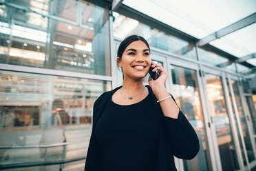 Beautiful young woman on business trip talking on cellphone at airport. Travelling woman making phone call. - JLPSF00895