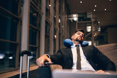 Traveler waiting at airport after flights delays and cancellations. Businessman asleep in airport lounge. - JLPSF00907