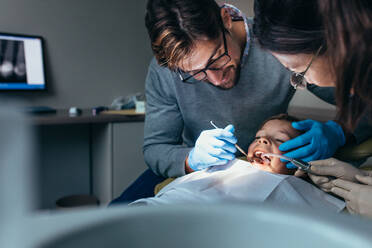 Zahnarzt mit Krankenschwester untersucht die Zähne eines Patienten in der Zahnklinik. Kleiner Junge wird zahnärztlich behandelt. - JLPSF00936