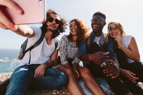 Eine Gruppe von Freunden ruht sich beim Wandern auf einem Berg aus und macht ein Selfie. - JLPSF00954