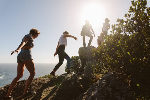 Gruppe von Freunden auf einem Berg. Junge Leute auf Bergwanderung an einem Sommertag. Männer und Frauen klettern auf Felsen. - JLPSF00967