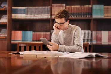 Junge Studentin mit digitalem Tablet und Kopfhörern in der Bibliothek. College-Studentin mit Tablet-PC in der Bibliothek. - JLPSF00997