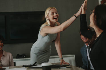 Businesswomen high five in a board room meeting. Happy business professionals having meeting in office conference room. - JLPSF01022