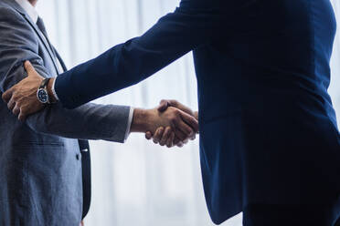 Anspruchsvolle Geschäftsleute schütteln sich nach einem Geschäft die Hände. Geschäftsleute schütteln sich die Hände und treffen eine Vereinbarung. - JLPSF01045