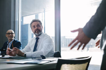 Senior office worker listening to manager during meeting in conference room. Businessman during meeting in office. - JLPSF01050