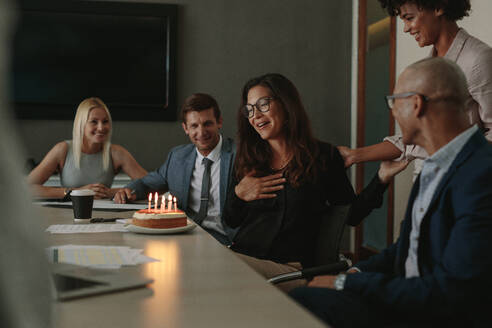 Büroangestellte feiern den Geburtstag einer Kollegin während einer Sitzung im Konferenzraum. Geschäftsteam feiert den Geburtstag eines Kollegen im Büro - JLPSF01056