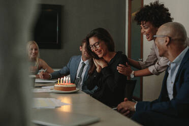 Geschäftsteam feiert den Geburtstag einer Kollegin mit Kuchen im Büro. Geburtstagsfeier einer Mitarbeiterin während einer Personalversammlung. - JLPSF01058