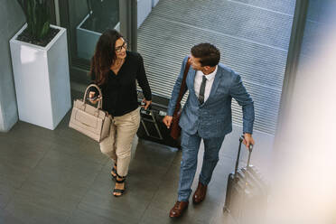 Businessman and woman walking together with baggage and talking. Business people arriving for conference. - JLPSF01067