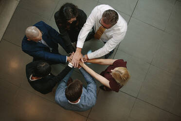 Top view of business people putting hands together. Multiracial business team stacking hands over each other. - JLPSF01071