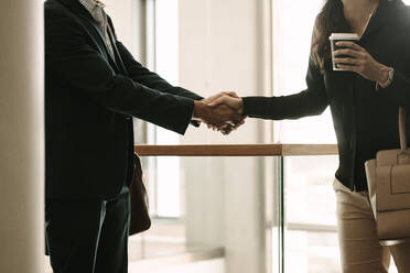 Business people shaking hands in office. Business colleagues handshaking and greeting. - JLPSF01079