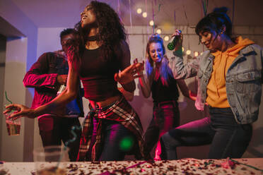 Freunde tanzen mit Getränken auf einer Hausparty. Junge Frauen genießen und haben Spaß auf einer Hausparty. - JLPSF01095