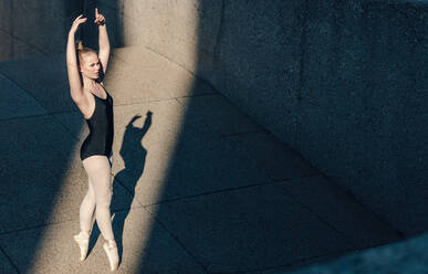 Ballet dancer practicing dance moves outdoors. Dancer standing tall on her toes in pointe shoes practicing her dance steps. - JLPSF01131