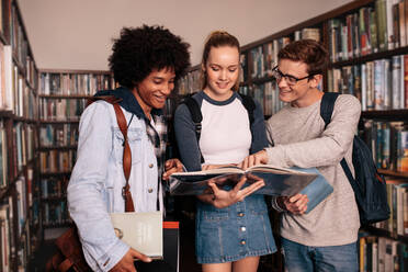 Eine Gruppe von Studenten diskutiert in der Bibliothek. Universitätsstudenten lernen zusammen in der Bibliothek. - JLPSF01152