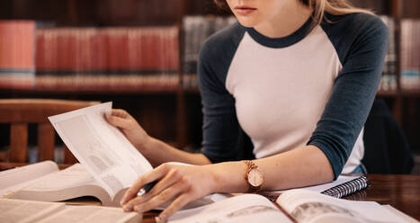 Nahaufnahme einer jungen Frau, die in der Bibliothek ein Buch liest. Ausschnitt einer jungen Studentin, die in der Bibliothek lernt. - JLPSF01158