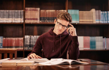 Studentin, die in der Bibliothek ein Buch liest. Junge Studentin, die sich in der Bibliothek auf eine Prüfung vorbereitet. - JLPSF01163