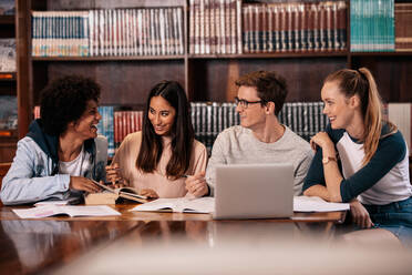 Eine Gruppe von Studenten sitzt am Tisch in der Bibliothek und lernt zusammen. Glückliche junge Freunde arbeiten an einem College-Projekt. - JLPSF01182