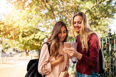 Universität weibliche Studenten lesen Nachricht auf Smartphone im Freien. Schöne Studenten Blick auf Handy. - JLPSF01218